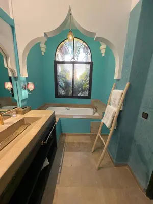 a bathroom with a tub and a window and a chair at Royal Moroccan House in Marrakech