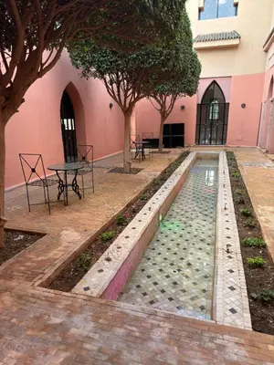 a pool in the courtyard of a building with trees at Royal Moroccan House in Marrakech