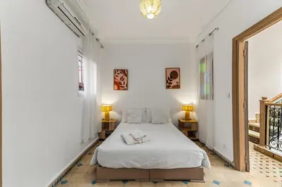 a white bedroom with a bed and two lamps at Riad melyssa in Marrakech