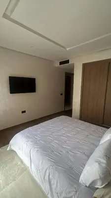 a bedroom with a white bed with a flat screen tv at High standing 2 minutes from Gueliz train station in Marrakech