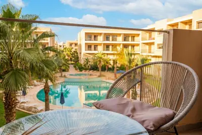 a balcony with a table and chairs and a swimming pool at Séjour luxueux pearl garden Marrakech in Marrakech