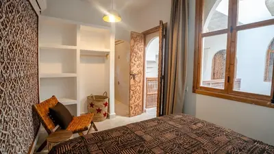 a bedroom with a bed and a window and a chair at Riad Lala Fatima - New & Exclusive - Pool & Breakfast in Marrakech