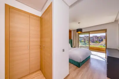 a bedroom with a bed and a sliding door at Family Apartment 3 Bedrooms Prestigia with Pool in Marrakech