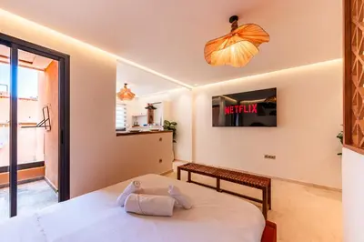 a bedroom with a bed and a tv on the wall at Cocon Balnéo de Gueliz - Central & Balcon in Marrakech