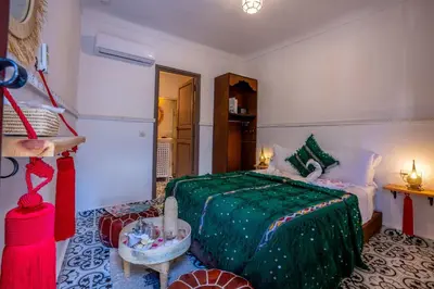a bedroom with a bed with a green blanket at Riad Nowara And Spa in Marrakech