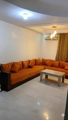 an orange couch in a living room with a table at Au Coeur de L'hivernage P21 in Marrakech