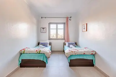 two beds in a small room with a window at Zou Appartement in Marrakech