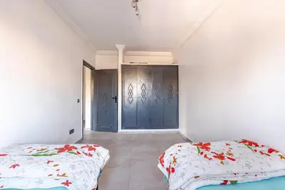 a bedroom with two beds and a blue door at Zou Appartement in Marrakech