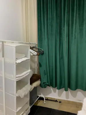 a bathroom with a green shower curtain and white shelves at Studio moderne et calme à Guéliz in Marrakech