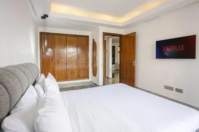 a bedroom with a white bed and a sliding door at Appart chic et calme avec vue dégagée in Marrakech