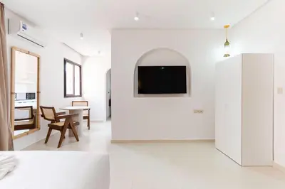 a white living room with a tv on a wall at Studio Horizon Marrakech Station in Marrakech
