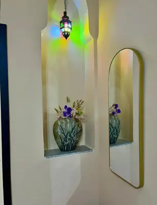 a mirror and a vase with flowers in a room at Spacieux Appart 2 chambres 6 Pers 12min Aéroport in Marrakech