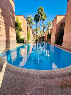a swimming pool in the middle of a building with palm trees at Lina Stay Riad Alkaria Assiyahia in Marrakech