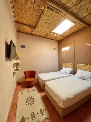 two beds in a room with a tv and a chair at Villa privée in Marrakech