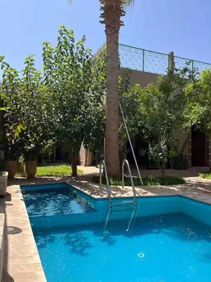 a swimming pool with a palm tree next to a building at Villa privée in Marrakech