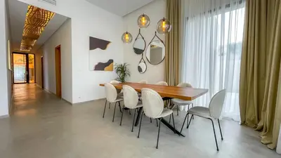a dining room with a wooden table and white chairs at Beautiful Villa Agathe with heated pool in Marrakech