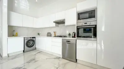 a kitchen with white cabinets and a washer and dryer at Superbe Villa Alma piscine chauffée à Marrakech in Marrakech