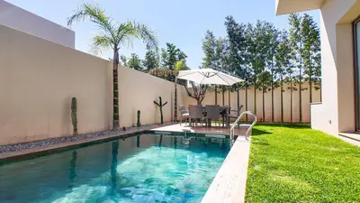a swimming pool in a yard with a table and an umbrella at Jade Villa with pool in Marrakesh in Marrakech