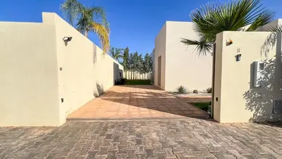 a pathway between two white buildings with a palm tree at Villa Amélia pool without opposite in Marrakech