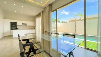 a kitchen and dining room with a glass table and a swimming pool at Villa Eden in Marrakech