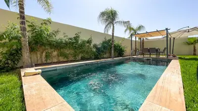 a swimming pool in a yard with palm trees at Villa Alya with heated pool in Marrakesh in Marrakech