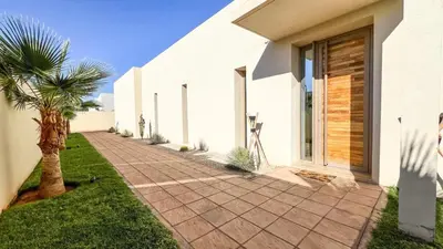 a walkway next to a white building with a palm tree at Villa Alya with heated pool in Marrakesh in Marrakech