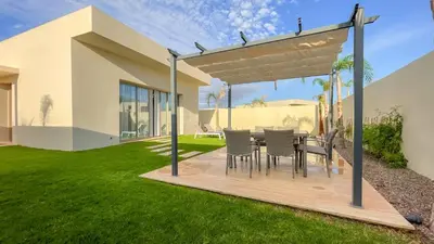 a table and chairs under a pergola in a yard at Villa Alya with heated pool in Marrakesh in Marrakech