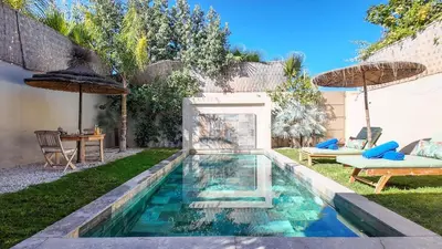 a swimming pool in a yard with a table and umbrellas at Aman Bungalow - heated pool, not overlooked in Marrakech