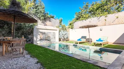a backyard with a pool with a table and an umbrella at Aman Bungalow - heated pool, not overlooked in Marrakech
