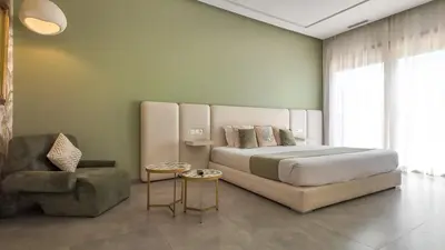 a bedroom with a large bed and a chair at Beautiful AWAL Villa, 6 suites & heated pool in Marrakech