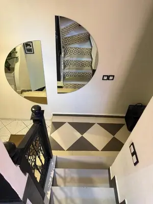 a spiral staircase with a round mirror on the wall at Beautiful modern triplex in Qariya Sayhia in Marrakech
