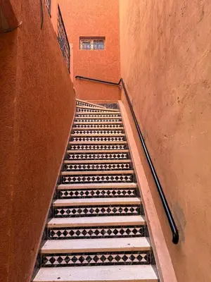 an empty staircase in an orange building with a stair case at Beautiful modern triplex in Qariya Sayhia in Marrakech