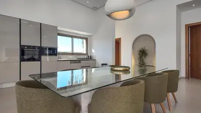 a dining room with a glass table and chairs at Villa Céleste avec piscine chauffée in Marrakech