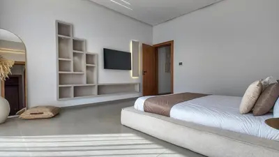 a white bedroom with a bed and a flat screen tv at Villa Céleste avec piscine chauffée in Marrakech