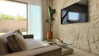 a living room with a couch and a tv on a stone wall at Majorelle Bungalow - Heated pool, not overlooked in Marrakech