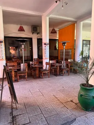 a restaurant with wooden tables and chairs and a potted plant at Appt Duplex dans village touristique, sublime vue, proche médina in Marrakech