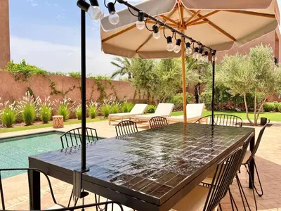 a table with an umbrella next to a pool at Villa Bohō - 4 suites in El Rhechat