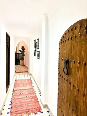 a hallway with a wooden door and a red rug at Riad Oumhani in Marrakech