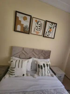 a bedroom with a bed with four pictures on the wall at Aéroport appartement Marrakech in Marrakech