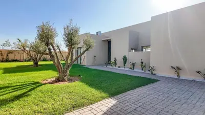 a white house with a tree in the yard at Villa Maréa heated pool not overlooked in Marrakech