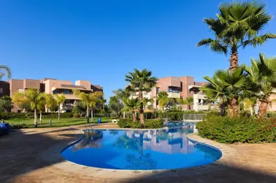 a resort pool with palm trees and buildings at Golf Prestigia Marrakech in Marrakech