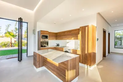 an open kitchen with wooden cabinets and a large window at Beautiful Villa 15 min Center, Jacuzzi, Padel in Marrakech