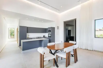a kitchen with a wooden table and white chairs at Heated Pool Absolute Luxury in Marrakech