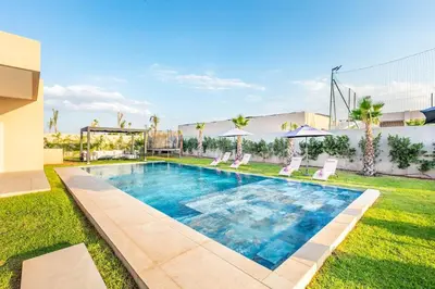 a swimming pool in a yard with chairs and a building at Heated Pool Absolute Luxury in Marrakech