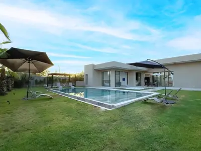 a swimming pool in front of a house with umbrellas at Dream Getaway Intimate Villa Private Pool in Marrakech