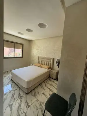 a bedroom with a large bed and a chair at Appartement à gueliz in Marrakech