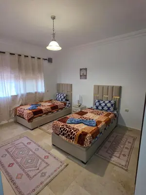 three beds in a room with rugs on the floor at apartt le Palmier de Guéliz in Marrakech
