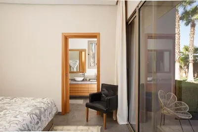 a bedroom with a bed and a chair and a mirror at Elegant 3-BR Villa with breakfast included in Marrakech