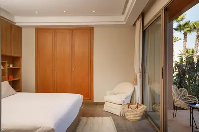 a bedroom with a white bed and a chair at Elegant 3-BR Villa with breakfast included in Marrakech