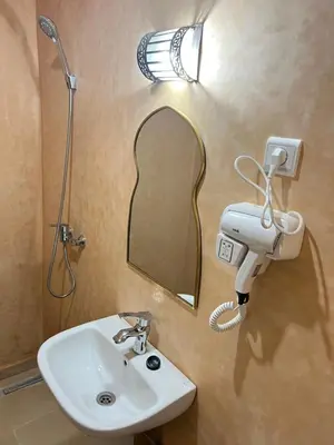 a bathroom with a sink and a mirror and a shower at Riad Lalla Nadia in Marrakech